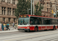 Red Toronto TTC streetcar on Queen Street with historic buildings and pedestrians in downtown Toronto, perfect example of affordable domestic travel Canada