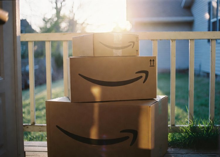 Stack of Amazon cardboard boxes on sunny front porch, shopping tip to always read 3-star and 4-star customer reviews before buying on Amazon