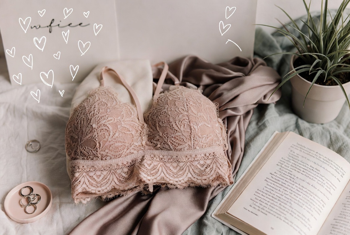 Tasteful cozy flat lay of soft blush lace bralette with self-care journal and plants, feminine relaxing aesthetic in pastel colors