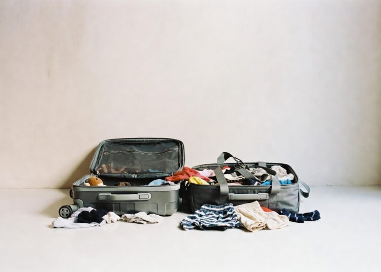 Two open suitcases overflowing with clothes on the floor, packing and travel organization tip for better suitcase packing techniques