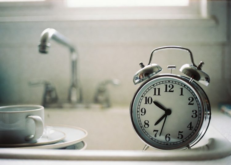 Vintage twin bell alarm clock on kitchen counter near sink, practical life hack to set a timer or alarm for daily kitchen chores and cleaning tasks