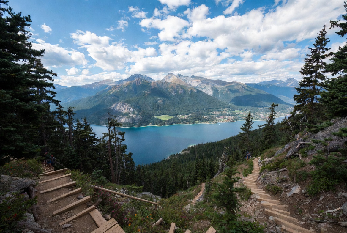 Wooden staircase hiking trail with panoramic view of large lake and mountains in British Columbia Canada
