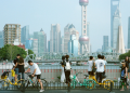A busy street scene in Shanghai with pedestrians and bicycles and and the citys modern skyline