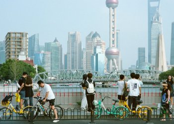 A busy street scene in Shanghai with pedestrians and bicycles and and the citys modern skyline
