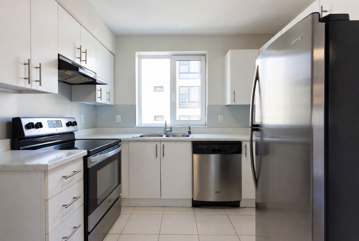 Clean modern kitchen with white cabinets stainless steel refrigerator stove oven dishwasher and bright natural lighting