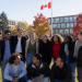 Diverse group of happy Canadian university students smiling together on a sunny autumn campus with Canadian flag waving in background