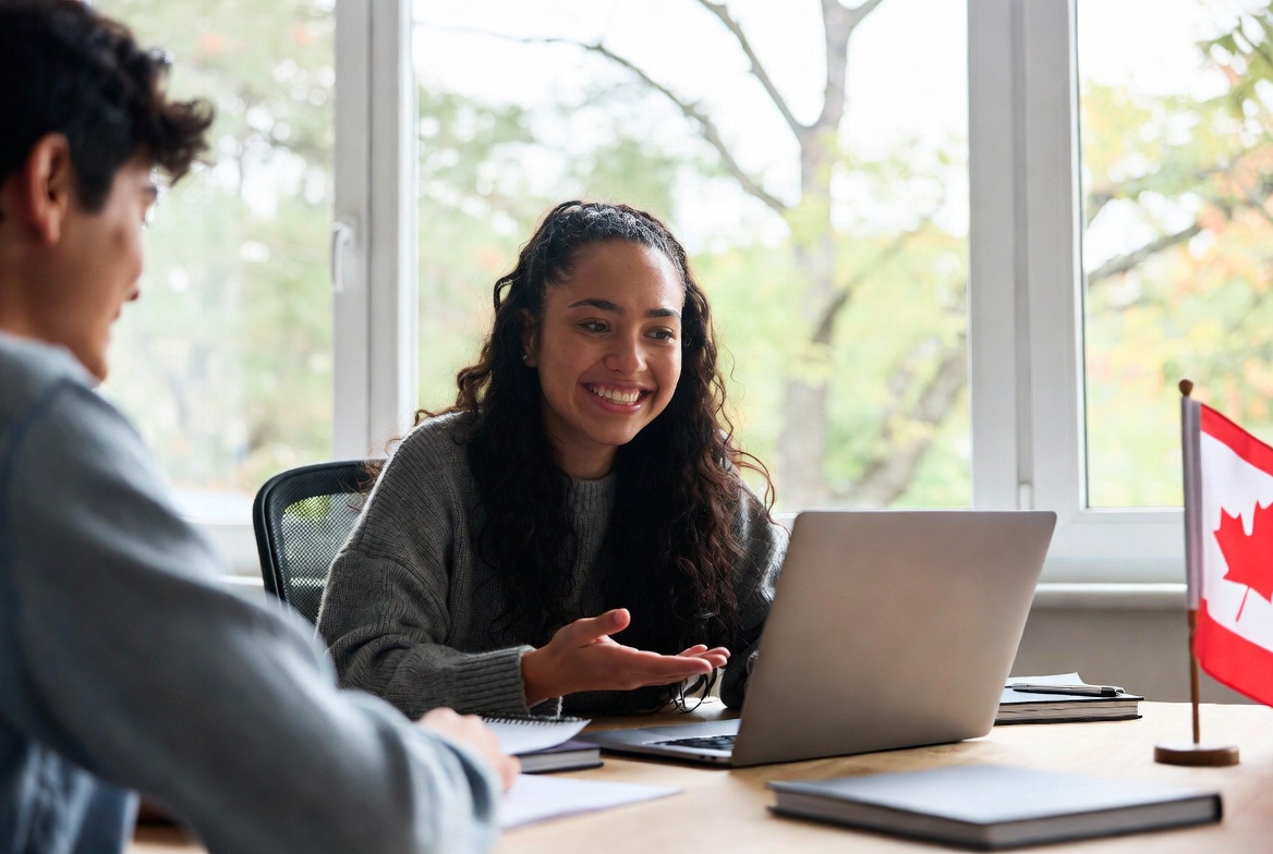 Smiling female tutor helping a student with laptop in a bright study room